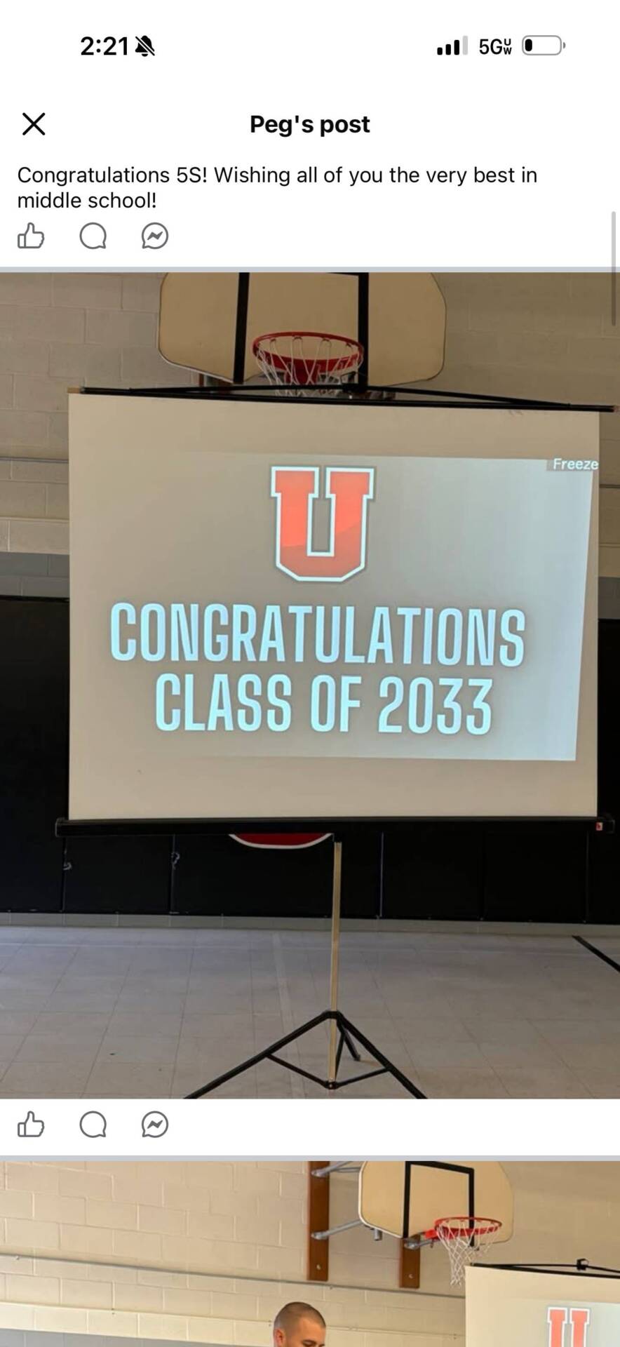 Projection screen in a school gym displays “Congratulations Class of 2033” during an elementary school promotion celebration.