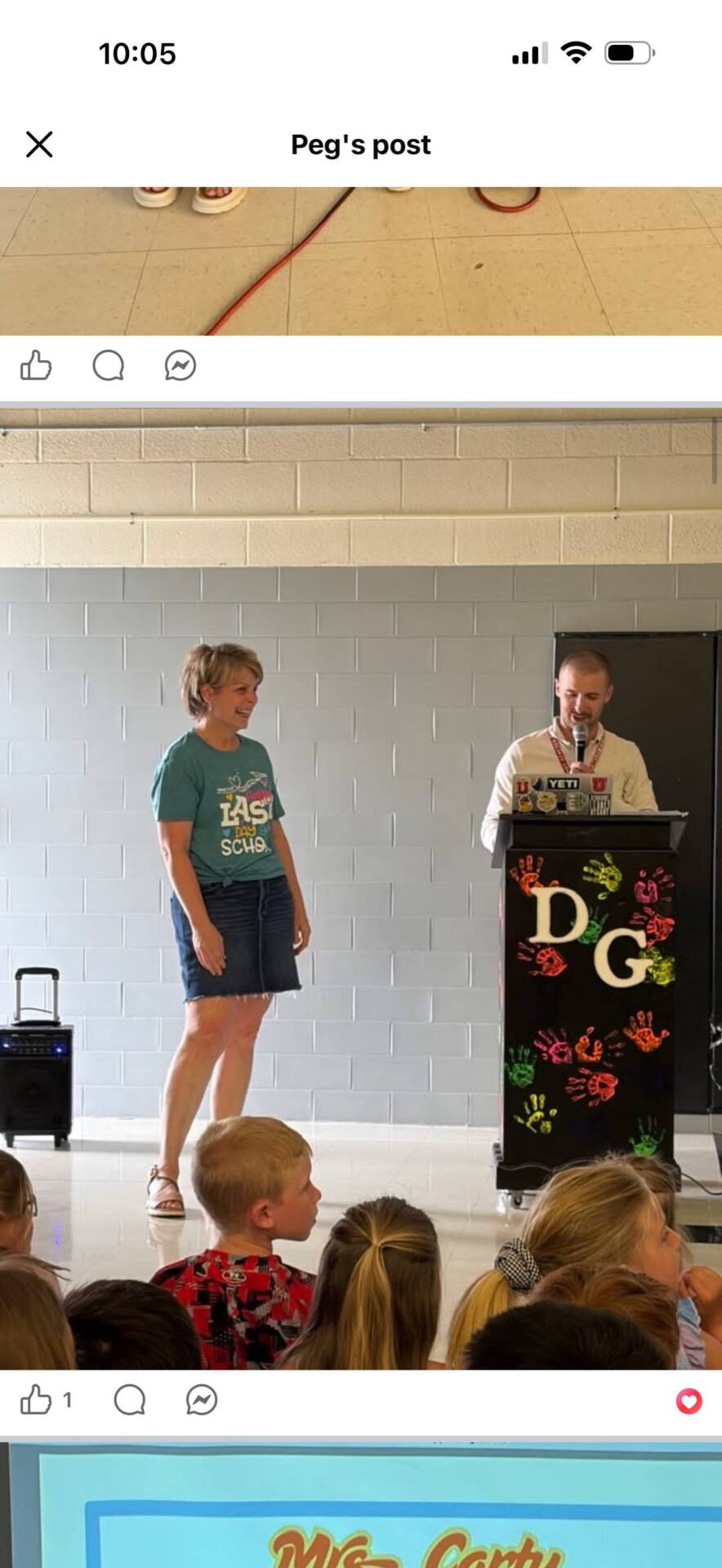School administrator stands beside a podium while speaking to students gathered for an elementary school promotion ceremony.