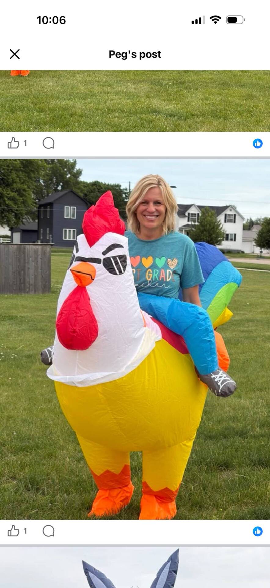Staff member smiles while wearing an inflatable chicken costume on a grassy field during a school celebration.