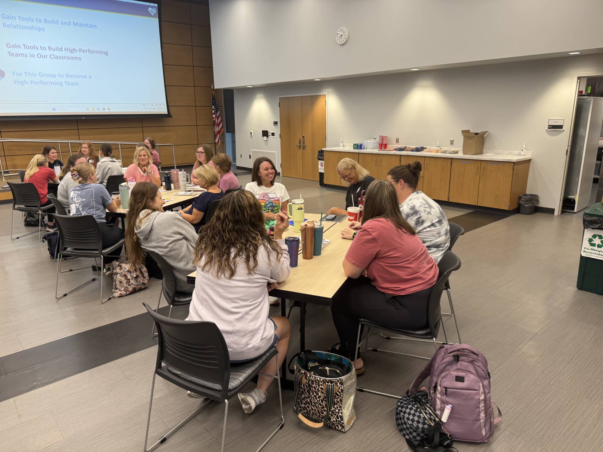 Educators collaborate in small groups around tables during a professional development session on building high-performing teams.