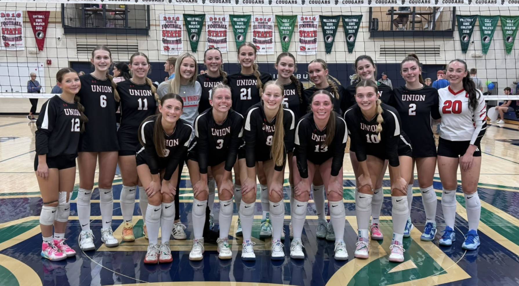Union volleyball players pose together on a gym court in black, white, and red uniforms.