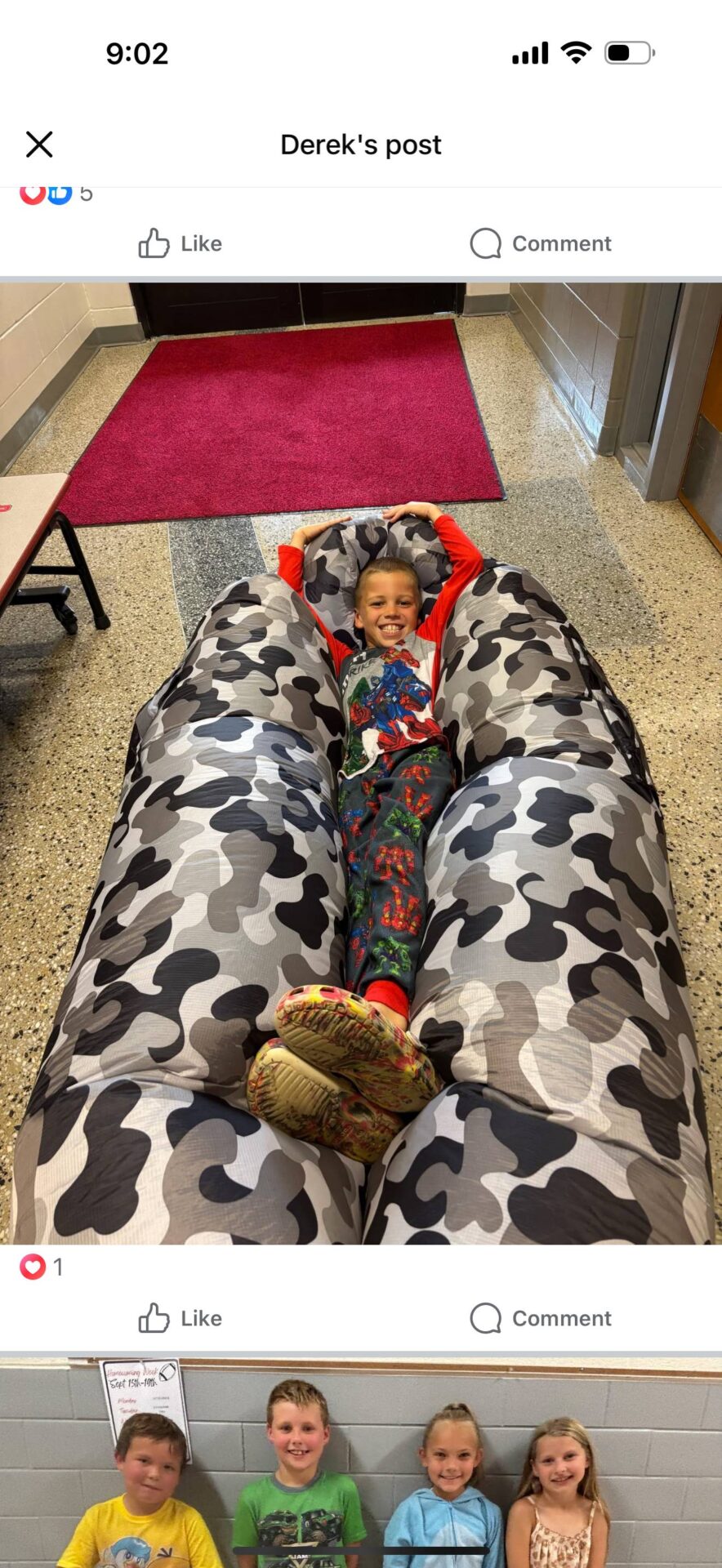 Young student in pajamas smiling while lying on a large camo-pattern lounge chair.