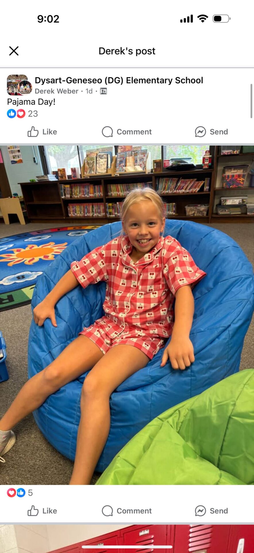 Student in red patterned pajamas sitting on a blue beanbag chair, smiling.