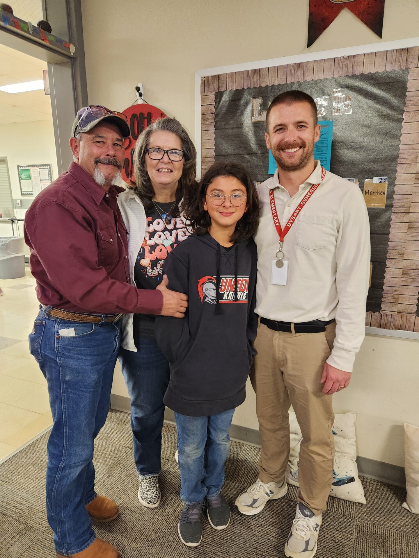 Student poses with two adults and a staff member inside the school.