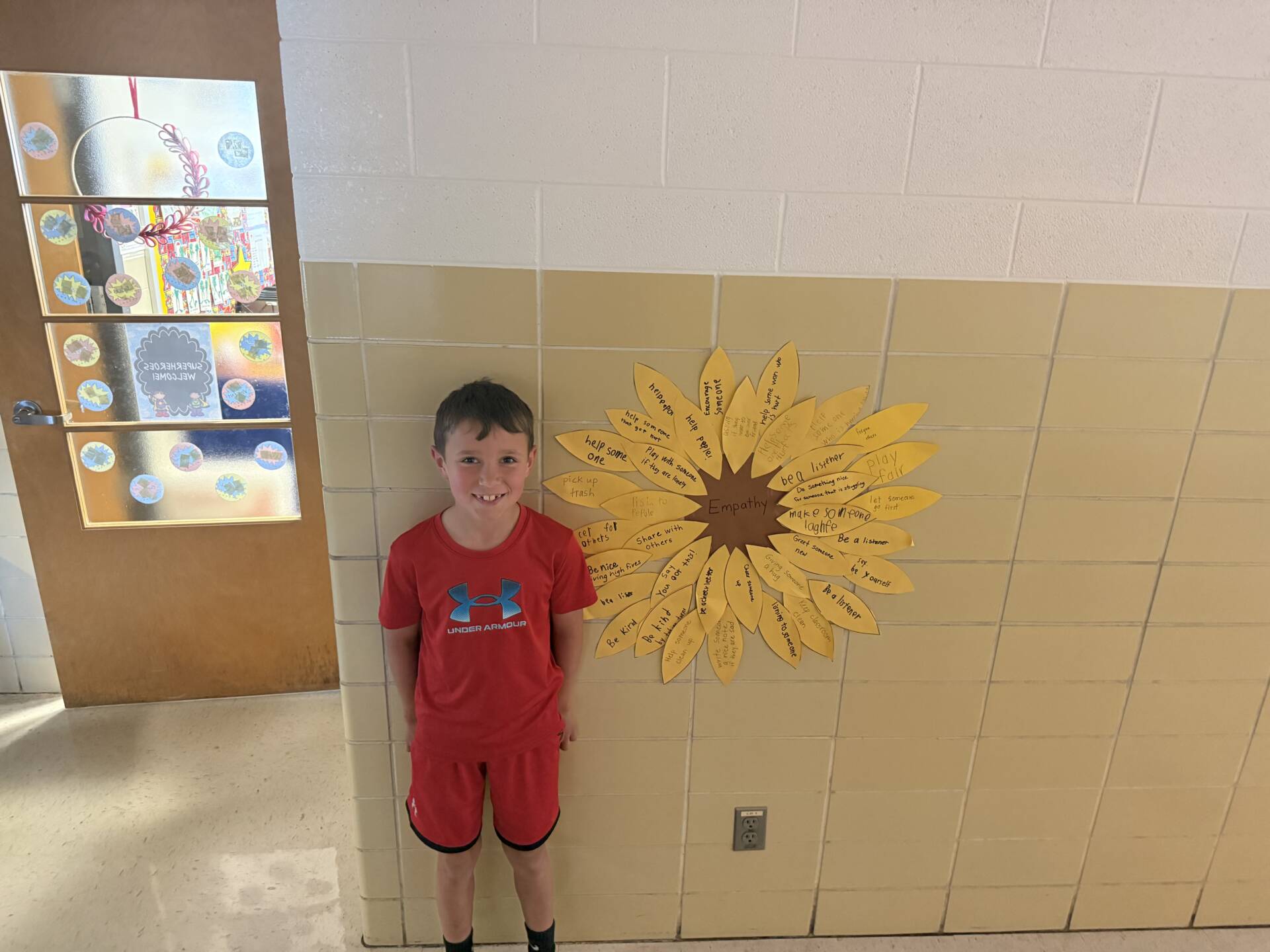 Student stands by a wall display shaped like a flower labeled “Empathy,” with positive actions written on petals.