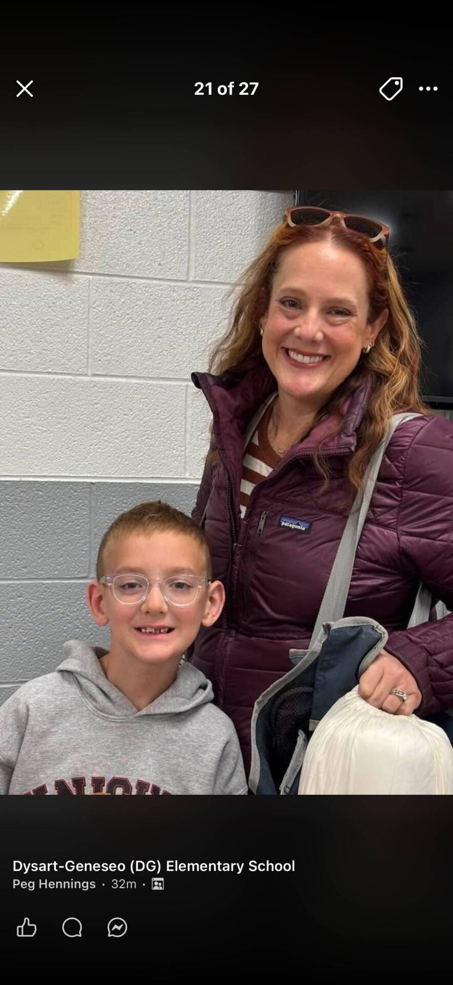 Student and adult smile together inside a school hallway during a school event or visit.