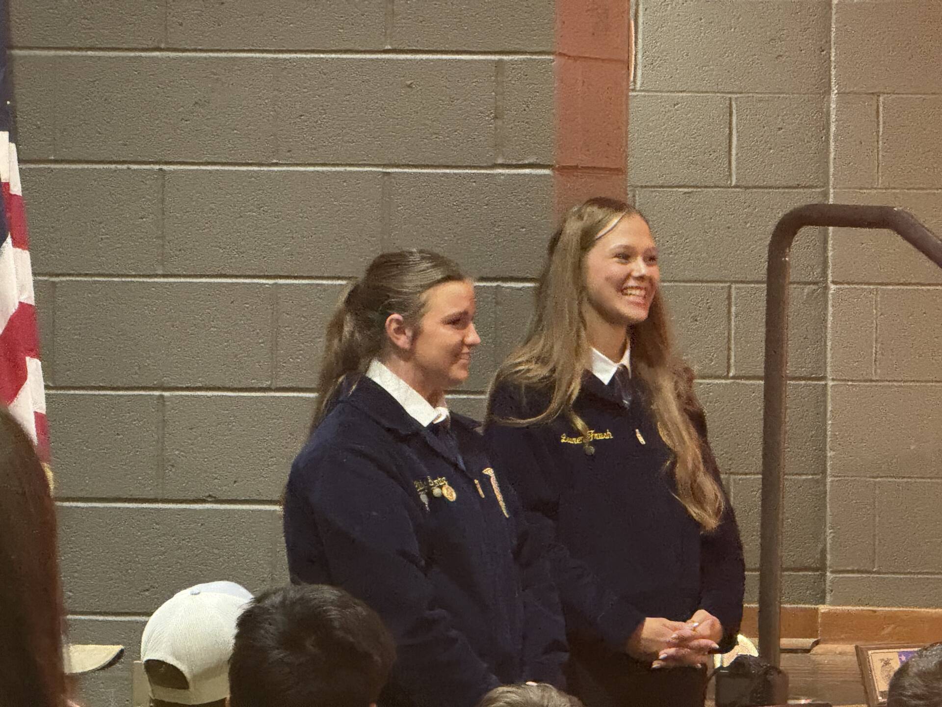 Two FFA students in blue jackets stand smiling during a school ceremony or presentation.