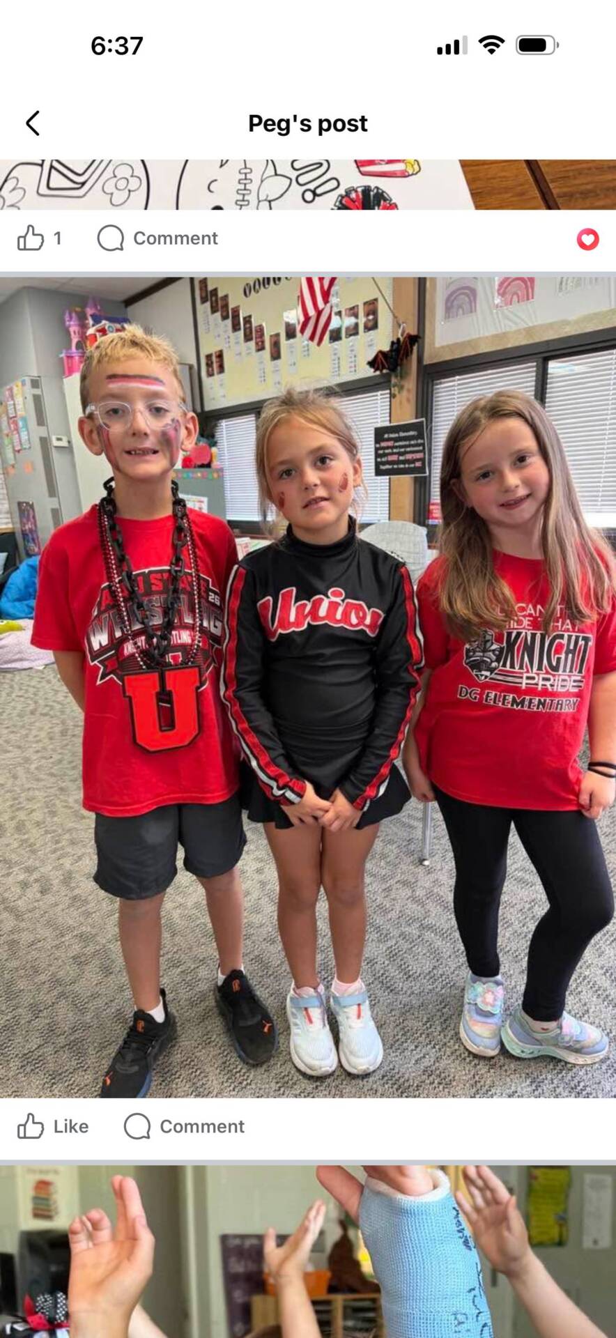 Three elementary students pose in red and black school spirit clothing, with face paint and smiles.