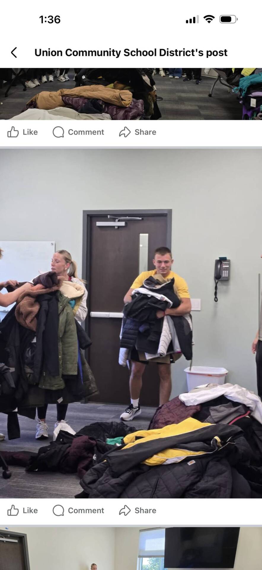 A student in a yellow shirt carries a large stack of donated coats during a school clothing collection event.